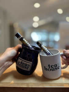 Two mugs with best dispensary near me 'The tea house' branding on a wooden surface.